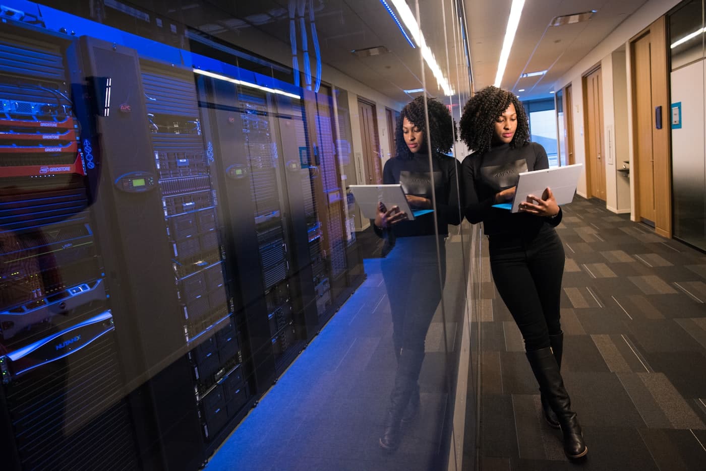 Operations specialist walking past a server room with a laptop